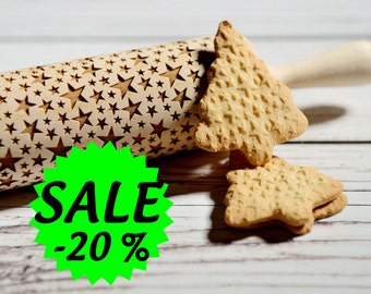 May include: A wooden rolling pin with a star pattern design. The rolling pin is next to two star-shaped cookies. A green circle with the text "SALE -20%" is in the foreground.