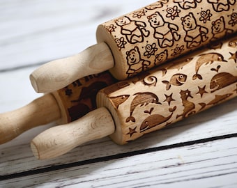 May include: Three wooden rolling pins with engraved designs. The top rolling pin has a Winnie the Pooh theme with bees and bears. The middle rolling pin has a seahorse and fish design. The bottom rolling pin has a whale and dolphin design.