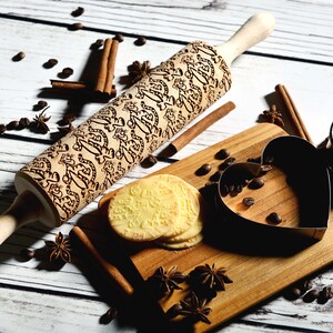 May include: A wooden rolling pin with a decorative engraved pattern, a heart-shaped cookie cutter, and a stack of cookies on a wooden cutting board. The board is surrounded by coffee beans, cinnamon sticks, and star anise.