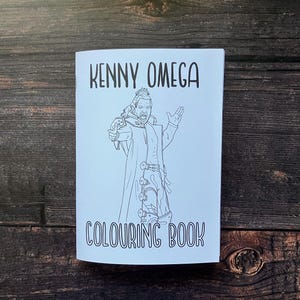 May include: Black and white colouring book featuring a line drawing of Kenny Omega, a professional wrestler, in a wrestling pose. The title of the book is "Kenny Omega Colouring Book".