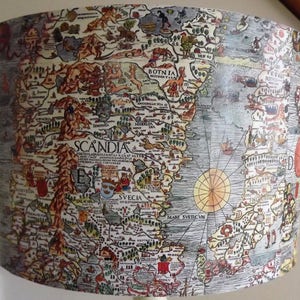 May include: A vintage-style map of Scandinavia, printed on a lampshade. The map is in shades of brown, blue, and green, with handwritten text in black. The map shows the regions of Norway, Sweden, and Finland, with the text "SCANDIA" in the center.