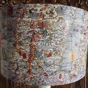 May include: A vintage map of Scandinavia, printed on a lampshade. The map is in a detailed, illustrated style, with a focus on the Scandinavian peninsula. The map is surrounded by a light blue border.