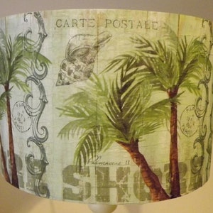 May include: A lampshade with a tropical theme featuring palm trees, a seashell, and the text "Carte Postale" and "Palmeraie II".