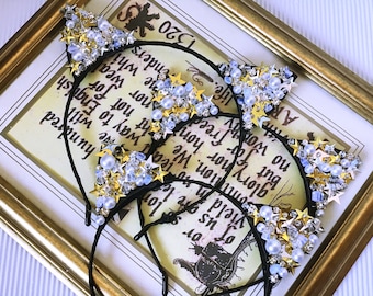 May include: Four black cat ear headbands with gold and blue embellishments. The embellishments include stars, rhinestones, and pearls.