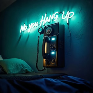 Puede incluir: Un teléfono rotatorio negro con un letrero de neón que dice "No you hang up" montado en una pared turquesa. El teléfono tiene un cable y un auricular.
