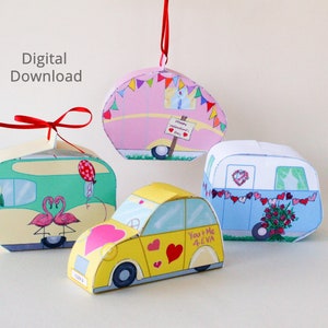 May include: Four papercraft Valentine's Day ornaments in the shape of a car, a camper, and two different styles of vintage trailers. The car is yellow with pink hearts and the text "You & Me 4eva". The camper is blue with a heart and a garland of hearts. One trailer is pink with a garland of flags and the text "Happy Valentine's Day". The other trailer is green with pink flamingos and a red balloon.