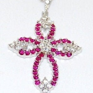 May include: A silver chain necklace with a pink and white crystal cross pendant.