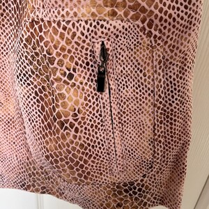 May include: A pink snakeskin-patterned jacket with a zippered pocket on the front.