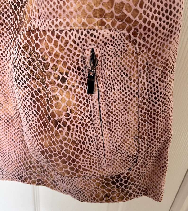 May include: A pink snakeskin-patterned jacket with a zippered pocket on the front.