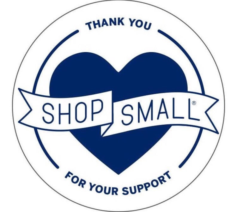 May include: A white circle with a blue heart in the center. The heart has a white banner that says "SHOP SMALL" with a registered trademark symbol. The circle also has the text "THANK YOU" at the top and "FOR YOUR SUPPORT" at the bottom.