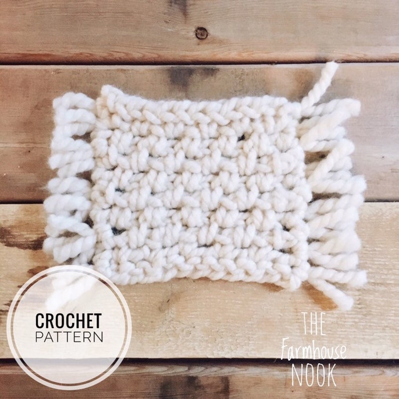 Pode incluir: Um quadrado de croch&ecirc; branco com franjas em dois lados. O quadrado est&aacute; sobre uma superf&iacute;cie de madeira. O texto "CROCHET PATTERN" est&aacute; em um c&iacute;rculo abaixo do quadrado. O texto "THE FARMHOUSE NOOK" est&aacute; abaixo do quadrado &agrave; direita.