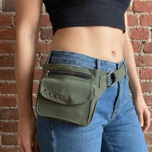 Könnte beinhalten: Olivgrüne Bauchtasche mit einem Reißverschluss-Hauptfach und einer kleineren Vordertasche. Die Tasche hat eine Metallschnalle und wird um die Taille getragen. Die Bauchtasche ist aus strapazierfähigem Stoff gefertigt.