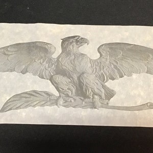 May include: A silver-toned eagle with outstretched wings perched on a branch. The eagle is a symbol of freedom and strength.