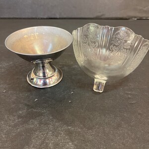 Peut inclure: Deux petits bols, l'un en argent et l'autre en verre transparent avec un motif d&eacute;coratif. Les bols sont sur une surface gris fonc&eacute;.