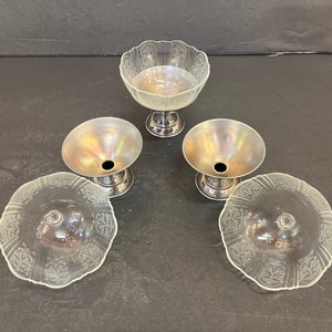 Peut inclure: Quatre coupelles &agrave; dessert en verre transparent avec des bases argent&eacute;es. Les coupelles ont un bord festonn&eacute; et un motif floral d&eacute;licat.