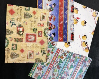 May include: Four different Christmas wrapping paper designs. The first design features a red, white and blue pattern with snowmen and a red truck. The second design features a yellow and brown pattern with a snowman, a sled, and the text "A Merry Christmas". The third design features a blue and green pattern with a snowman and the text "Joy of the Season". The fourth design features a white background with a red and white candy cane pattern and a snowman.
