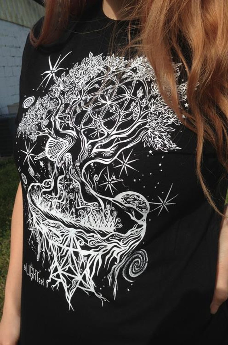 Pode incluir: Camiseta preta com um gr&aacute;fico branco de uma &aacute;rvore com ra&iacute;zes e galhos intrincados. A &aacute;rvore &eacute; cercada por estrelas e uma lua crescente. O texto "all light" &eacute; vis&iacute;vel na parte inferior do design.