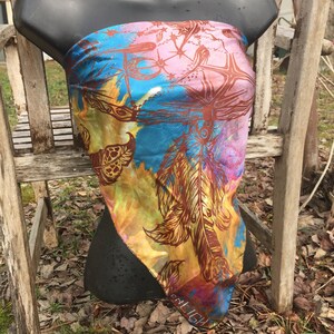 May include: A colourful silk scarf with a feather design in shades of brown, yellow, pink, and blue. The scarf has a fringed edge and the word "MILIGU" is visible at the bottom.
