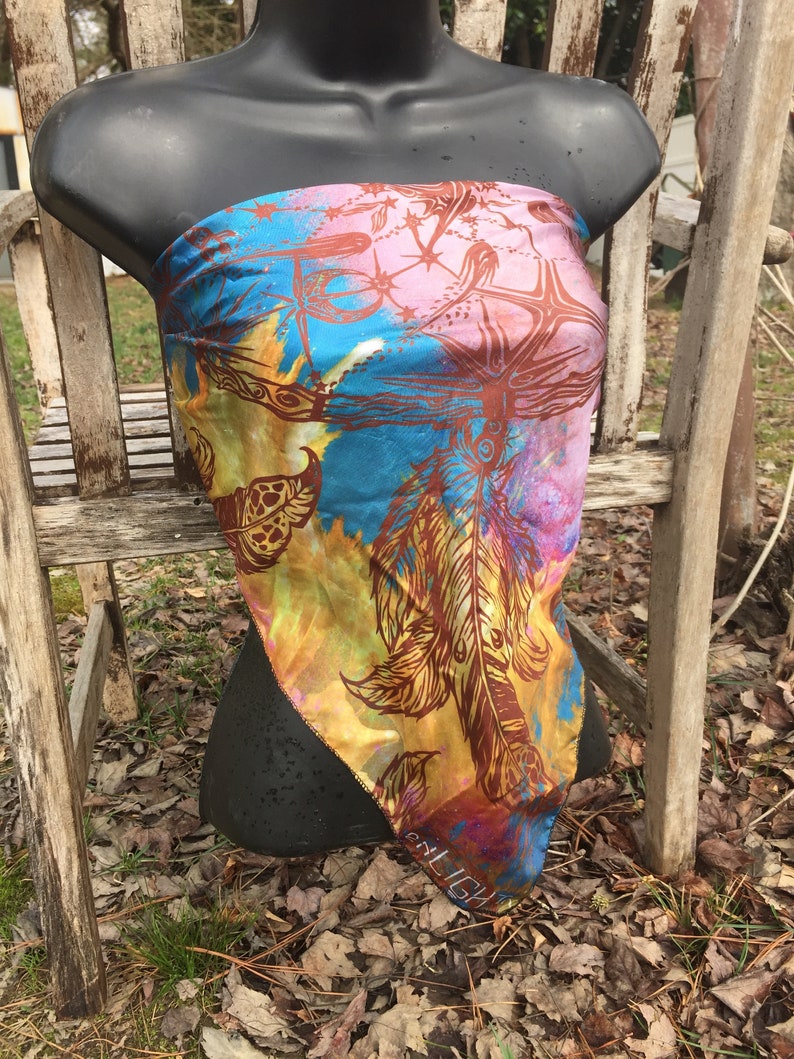 May include: A colourful silk scarf with a feather design in shades of brown, yellow, pink, and blue. The scarf has a fringed edge and the word "MILIGU" is visible at the bottom.
