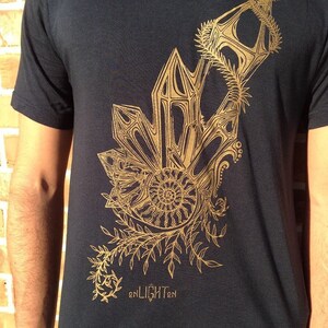 May include: A black t-shirt with a gold graphic design of a stylized plant with a spiral in the center. The text "enLIGHTen" is printed below the graphic.
