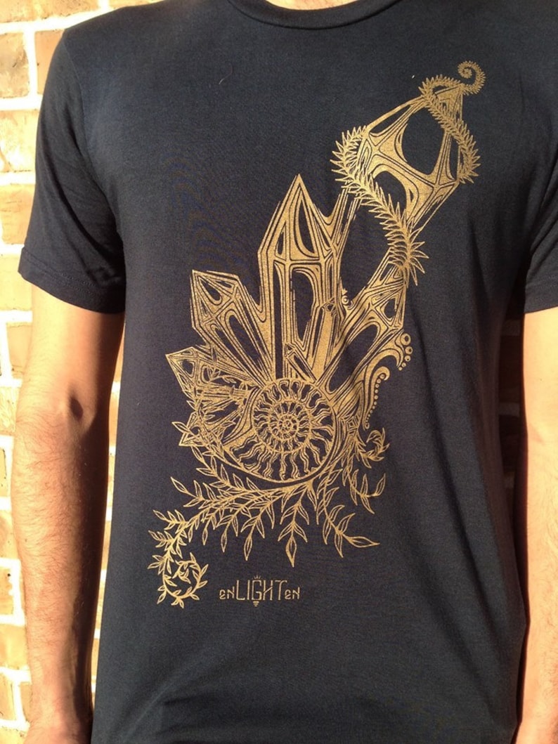 May include: A black t-shirt with a gold graphic design of a stylized plant with a spiral in the center. The text "enLIGHTen" is printed below the graphic.