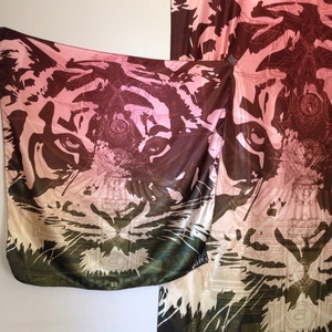 May include: A silk scarf with a tiger face design. The scarf features a gradient of colors, including pink, brown, and green. The tiger's face is prominently displayed, with intricate details and patterns. The scarf is a stylish accessory.