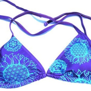 May include: Purple bikini top with a blue and white sunflower print. The top has adjustable straps and a triangle shape.