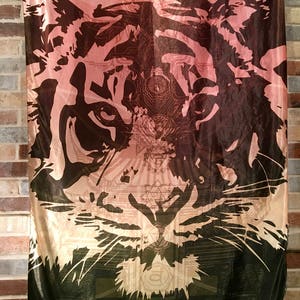 May include: A rectangular tapestry featuring a detailed tiger face design. The artwork transitions from a dark brown at the top to a light pink and then to a dark green at the bottom. The word "enLIGHT" is printed at the bottom.