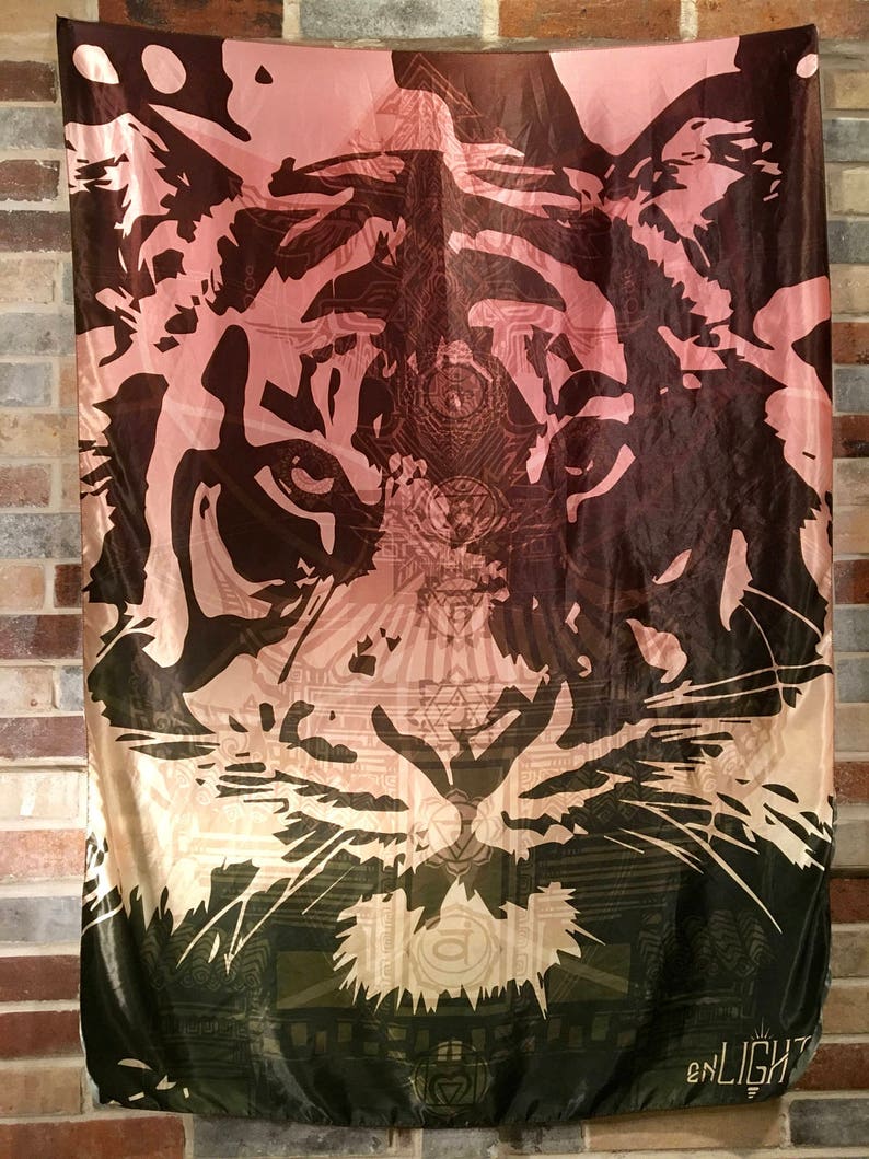 May include: A rectangular tapestry featuring a detailed tiger face design. The artwork transitions from a dark brown at the top to a light pink and then to a dark green at the bottom. The word "enLIGHT" is printed at the bottom.