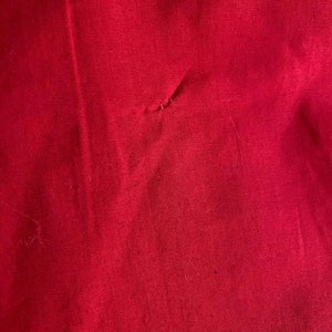 May include: A close-up of a solid red fabric with a small hole in the center.