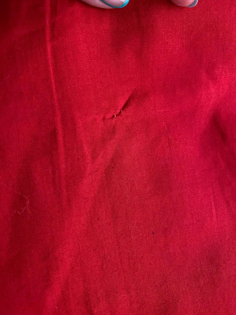 May include: A close-up of a solid red fabric with a small hole in the center.