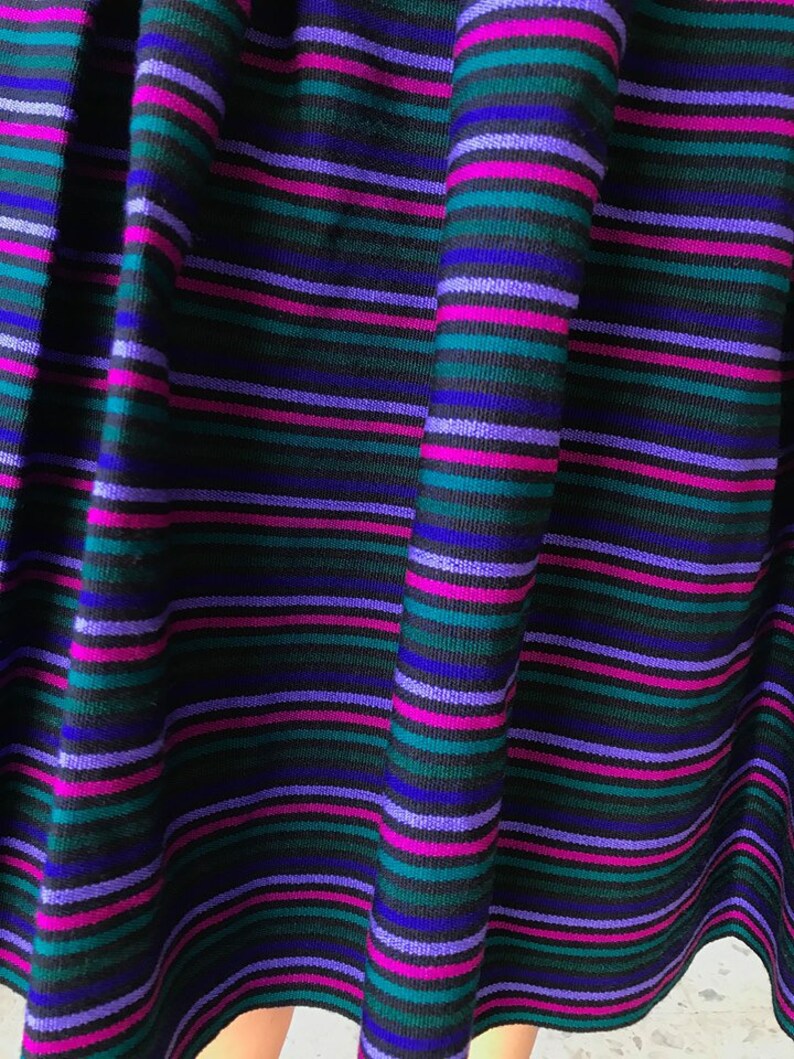 May include: A black skirt with horizontal stripes in shades of purple, blue, and green.