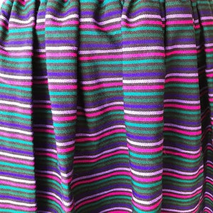 May include: A black skirt with horizontal stripes in shades of purple, pink, teal, and white.