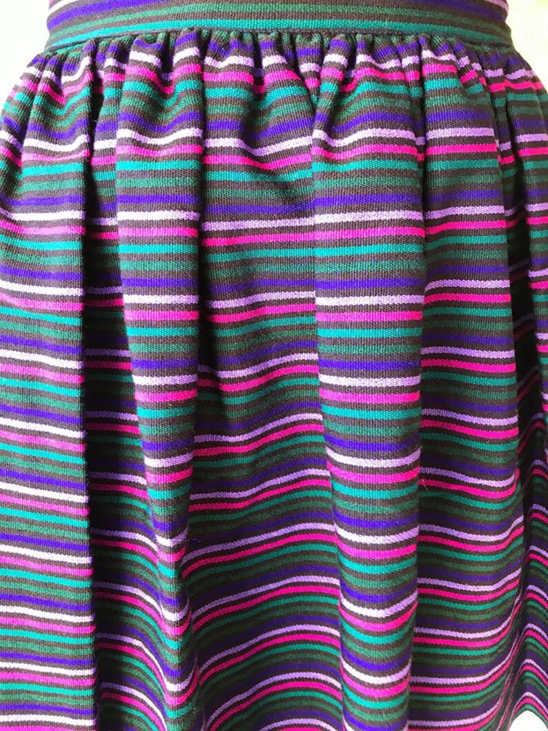 May include: A black skirt with horizontal stripes in shades of purple, pink, teal, and white.
