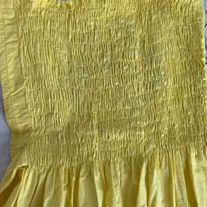 May include: A yellow sundress with a smocked bodice and a gathered skirt.