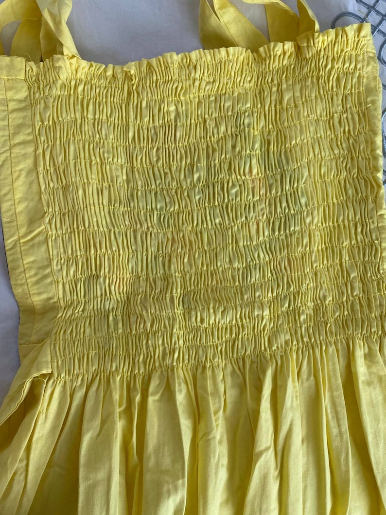 May include: A yellow sundress with a smocked bodice and a gathered skirt.