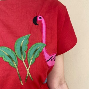 May include: Red cotton dress with embroidered pink flamingo and green palm leaves.