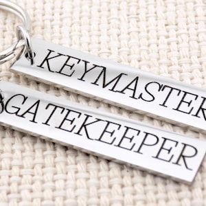 May include: Two silver keychains with the words "Keymaster" and "Gatekeeper" engraved on them.