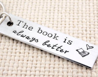 May include: Silver keychain with the text "The book is always better" and a small heart and open book graphic.