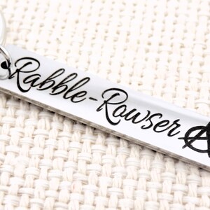 May include: Silver keychain with the text "rabble-rouser" and an anarchy symbol.