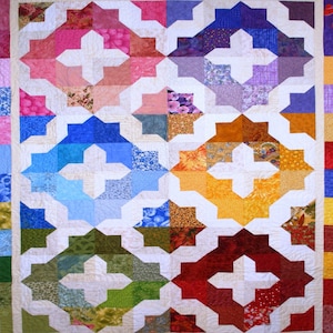 May include: A colorful quilt with a white background and a pattern of interlocking crosses. The quilt is made up of squares of different colors and patterns, including red, orange, yellow, green, blue, purple, and pink.