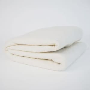 Könnte beinhalten: Gefalteter weißer Stoff, möglicherweise eine Decke oder Steppwatte, ist im Bild gestapelt. Der Stoff wirkt weich und dick, mit einer leicht strukturierten Oberfläche. Die Falten erzeugen sichtbare Schichten.