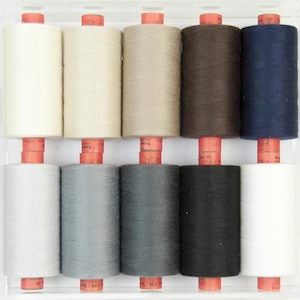 Puede incluir: Un recipiente de plástico transparente contiene diez carretes de hilo de varios colores. Los colores del hilo incluyen blanco, crema, beige, marrón, azul marino, gris claro, gris, gris oscuro, negro y blanquecino. Cada carrete está montado sobre una base roja.