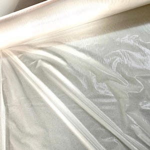 Könnte beinhalten: Eine Rolle durchsichtigen, durchscheinenden, irisierenden Stoffes. Der Stoff ist transparent und hat einen leichten Schimmer.