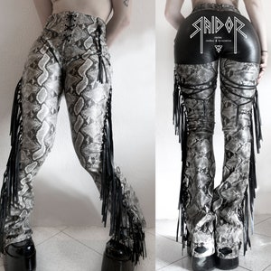 May include: Black and white snake print pants with black fringe and a black leather waistband with the text "STRIDOR" in white.