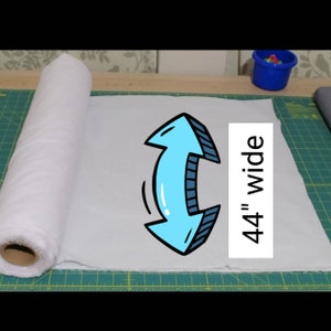 May include: A white fabric roll, 44 inches wide, is unrolled on a green cutting mat. The fabric is light blue and has a blue arrow pointing to the right, indicating the direction of the fabric's width.
