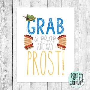 May include: A white printable sign with blue and yellow text that says "Grab a prop and say Prost!"  There are two red and brown accordions on either side of the text.  The sign is on a wood background.