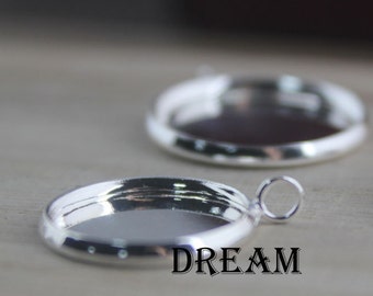 May include: Two silver-toned metal pendant trays with a round shape and a smooth, shiny finish. The trays have a lip around the edge and a small loop at the top for hanging.
