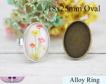 May include: A silver ring with a 18x25mm oval shaped glass cabochon featuring a floral design with pink, yellow, and white flowers. The ring is made of alloy metal.