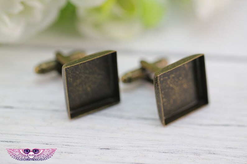 May include: A pair of antique gold cufflinks with square settings. The cufflinks are made of metal and have a vintage look.